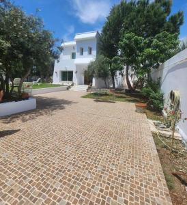 a brick walkway in front of a white house at Villa à yasmine hammamet in Nabeul