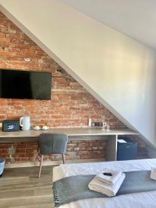 a bedroom with a brick wall with a tv and a chair at Dangė Hotel in Klaipėda