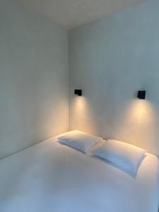 Una cama blanca con 2 almohadas y luces. en Edville Studio en Gante