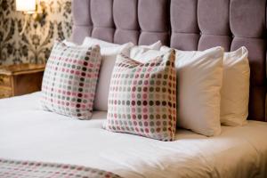 a bed with four pillows on it at Sweeney Hall Hotel in Oswestry