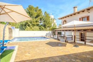 a pool with an umbrella and a house at Villa Pons in Playa de Muro
