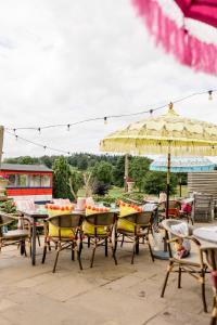 a patio with tables and chairs and an umbrella at Sweeney Hall Hotel in Oswestry