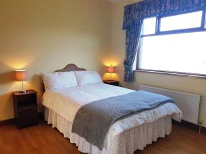 een slaapkamer met een bed met 2 lampen en een raam bij Pooreen House in Inverin