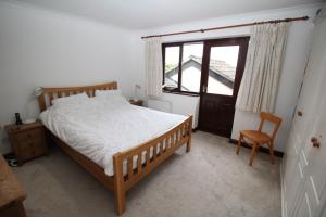 ein Schlafzimmer mit einem Bett, einem Fenster und einem Stuhl in der Unterkunft Acer in Corfe Mullen