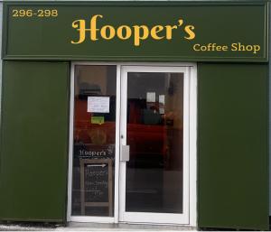 a green storefront of a coffee shop with glass doors at Hooper's Sandy Beach Guest Rooms in Swansea