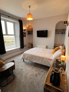 ein Schlafzimmer mit einem Bett und einem TV an der Wand in der Unterkunft Hoopers Sandy Beach Guest Rooms in Swansea