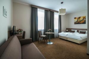 une chambre d'hôtel avec un lit et un canapé dans l'établissement Hotel Biały Domek, à Wałcz