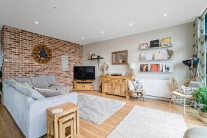 a living room with a couch and a brick wall at Luxury Huge Modern Open Plan 2Bedroom Flat - Free Private Parking & Balcony located at the OVO Hydro and SEC Centre in Glasgow