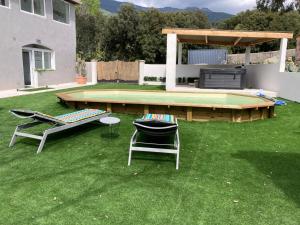 a yard with two chairs and a table and a pool at Les jardins de Funtanone T3 in Vignale