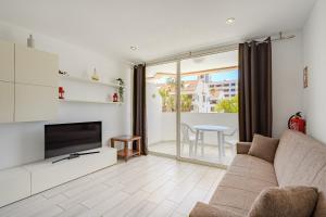 een woonkamer met een bank en een televisie bij Un dormitorio en Playa de las Américas in Adeje