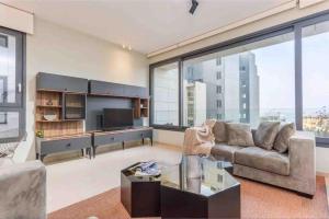 a living room with a couch and a large window at Luxurious Saifi 477, 2-BR Apt in Beirut