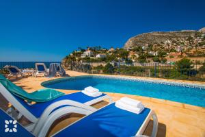 uma piscina com duas mesas e cadeiras junto ao oceano em Villa Timeris by Abahana Villas em Calpe