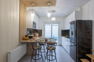 a kitchen with a island with bar stools and a refrigerator at --OFFRE SPECIALE-- LOFT COZY 77 --NEW--Jaccuzi CONFORT Terrasse Parking Wifi - 3 CH et 2 SDB - Aéroport CDG - Disneyland Paris in Annet-sur-Marne
