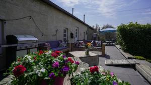 Un patio con un sofá y flores y una estufa. en SintPieter17 Lo-Ghis vakantiewoning, en Voeren