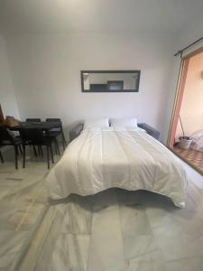 ein weißes Bett in einem Zimmer mit einem Tisch in der Unterkunft Primera Línea Playa Benalmádena in Benalmádena