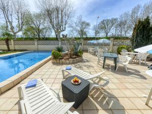 a patio with chairs and tables and a pool at Apartment Muga-2 by Interhome in Empuriabrava