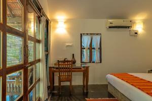 a bedroom with a desk and a bed and a window at The Bay Agonda in Agonda