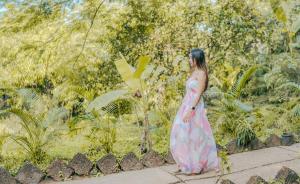 a woman in a pink dress walking down a sidewalk at The Bay Agonda in Agonda
