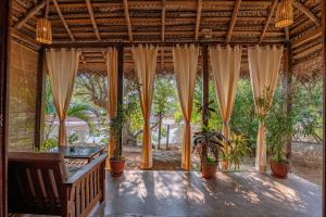 a porch with curtains and potted plants on it at The Bay Agonda in Agonda