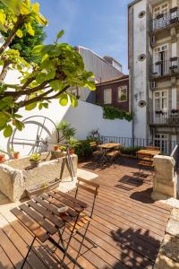 eine Holzterrasse mit Tischen und Stühlen auf einem Gebäude in der Unterkunft Porto Lounge Hostel & Guesthouse by Host Wise in Porto