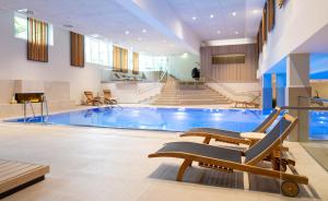 a pool in a hotel with chairs and stairs at Kongresshotel Potsdam am Templiner See in Potsdam