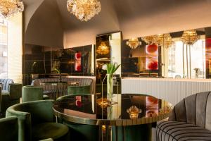 a restaurant with green chairs and a table and chandeliers at Bra Hotel in Bari