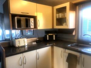 a kitchen with white cabinets and a black counter top at Rivington Retreat in Heysham