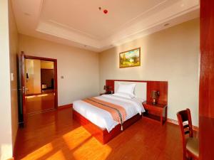 a bedroom with a white bed and a wooden floor at Notis International Hotel 诺蒂斯国际酒店 in Phnom Penh
