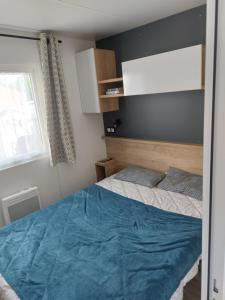 a bedroom with a bed with blue sheets and a window at mobil home jordy a gastes 714 in Gastes