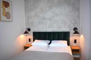 a bedroom with a large bed with a green headboard at Apartos Seaside Garden Luxury Apartments in Świnoujście