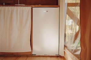 a white refrigerator in a room next to a window at Glamping Mazury - Przystań Jeziorany in Jeziorany