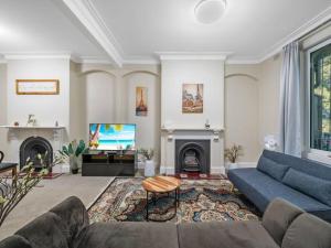 a living room with a blue couch and a tv at 4 bdrms house ICC & Darling Harbour & central & CBD & China Town in Sydney