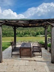 a picnic table and benches under a wooden pergola at Studio au cœur du Verdon in La Palud sur Verdon
