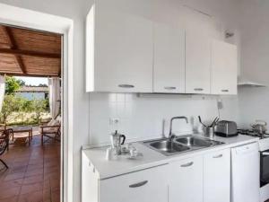 una cocina con armarios blancos y fregadero en Holiday Home 'Su Faru' estate-3 by Interhome, en Pula