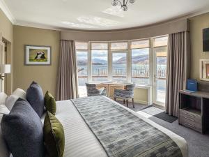 ein Schlafzimmer mit einem großen Bett und einem Tisch mit Stühlen in der Unterkunft The Royal Hotel in Ullapool