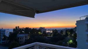 een uitzicht vanaf het balkon van een stad bij zonsondergang bij Ρετιρέ με θέα στη θάλασσα της Γλυφάδας in Athene