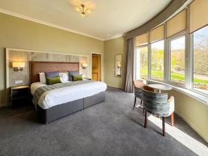1 dormitorio con 1 cama grande, mesa y sillas en The Royal Hotel en Ullapool