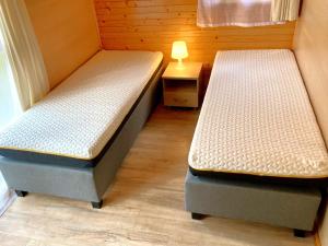 two beds in a room with a lamp on a table at Leśna Przystań in Pobierowo