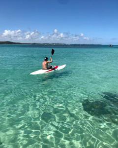 Ein Mann, der auf einem Surfbrett im Wasser sitzt. in der Unterkunft Angá Beach Hotel in São Miguel dos Milagres