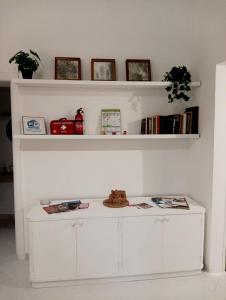 a white shelf with books and a white table at Valerio's Flat in Pozzuoli