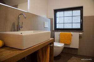 ein Bad mit einem Waschbecken, einem WC und einem Fenster in der Unterkunft Ferienwohnungen - Alte Brauerei in Rauhenebrach