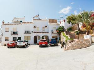 una gran casa blanca con coches aparcados en un aparcamiento en Tipica Casa En Frigiliana con patio y terraza, en Frigiliana