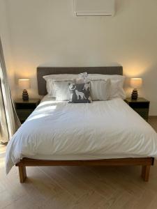 a bed with white sheets and pillows with two lamps at Chasselas Self Catering in Cape Town +12 photos