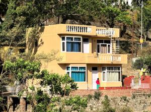 a woman standing in front of a yellow house at Villa Kartina by the Hillstay in Bhowāli