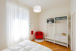 une chambre avec un lit et une chaise rouge dans l'établissement CONFALONIERI21 Isola cozy apartment by Hospity, à Milan