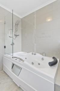 a white bathroom with a large white bath tub at Matakana Motel in Matakana