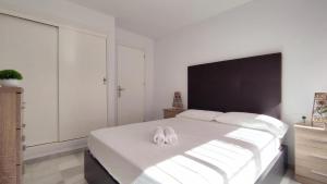 トレ・デル・マールにあるFantástico apartamento totalmente renovadoのベッドルーム1室(大きな白いベッド1台、スリッパ2枚付)