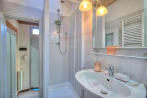 a white bathroom with a sink and a shower at Appartamento Gabriella - Happy Rentals in Laveno-Mombello
