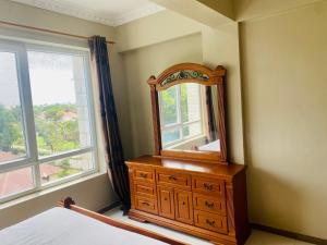 ein Schlafzimmer mit einem Spiegel, einer Kommode und einem Fenster in der Unterkunft Platinum apartment in Daressalam