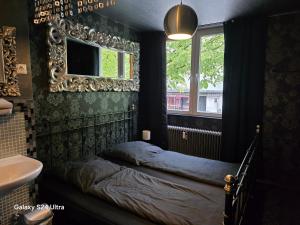 a bedroom with a bed and a mirror and a sink at Hostel Kiezbude in Hamburg
